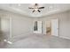 Large carpeted bedroom with a trey ceiling, ceiling fan, and doors to the en suite and closet at 4145 Essex Pond Way, Cumming, GA 30040