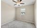 This is a cozy carpeted bedroom with neutral walls, ceiling fan, and a window with neighborhood views at 4145 Essex Pond Way, Cumming, GA 30040