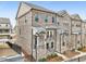 View of brick townhome featuring multiple stories, iron balconies and landscaped grounds at 4145 Essex Pond Way, Cumming, GA 30040