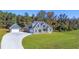 Aerial view of a gray home, detached garage, long driveway, and lush lawn surrounded by trees at 101 Red Oak Ln, Carrollton, GA 30116