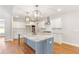 Bright kitchen with white cabinets, marble countertops, large island, modern lighting, and stainless steel appliances at 101 Red Oak Ln, Carrollton, GA 30116