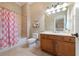 Well-lit bathroom offers a wooden vanity and a shower with a pink and white curtain at 6191 Talmadge Run, Acworth, GA 30101