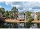 Beautiful waterfront homes nestled among mature trees with a serene lake view under a partly cloudy sky at 6191 Talmadge Run, Acworth, GA 30101