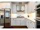 Close up of kitchen with stainless steel appliances, gas cooktop, white cabinets, and herringbone backsplash at 1560 Tapestry Rdg, Lawrenceville, GA 30045