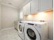 Well-lit laundry room with white cabinets above the washer and dryer, and marble tiled floor and granite countertops at 1560 Tapestry Rdg, Lawrenceville, GA 30045