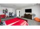 Spacious bedroom with a red bed, gaming setup, and dresser at 1055 Leadenhall St, Alpharetta, GA 30022