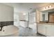 Spa-like bathroom with double vanities, a large tub, and a view into the bedroom at 301 Delta Dr, Mcdonough, GA 30252