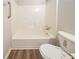 Close up view of a bathroom featuring a shower-tub combo, toilet, and wood look floors at 3332 Fannin Ct, Lithonia, GA 30038