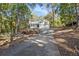 A long driveway leads to this two-story home with a two-car garage and metal roof, surrounded by trees at 34 Clay Ct, Villa Rica, GA 30180