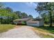 View of the side of a single-story home with a two-car garage, a gravel driveway and landscaped lawn at 2334 Highway 278, Social Circle, GA 30025