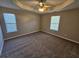 Spacious main bedroom boasts tray ceilings, fan, neutral walls, carpet, and two large windows at 6531 Gina Agha Cir, Lithonia, GA 30038