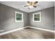 Relaxing bedroom showcasing wood-look floors, a ceiling fan, and ample natural light from two windows at 2436 Clarissa Nw Dr, Atlanta, GA 30318
