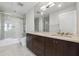 Modern bathroom featuring dual sinks, a bathtub with shower, and neutral-toned tiling at 3325 Piedmont Ne Rd # 1708, Atlanta, GA 30305