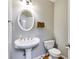 Well-lit half-bath features a pedestal sink, oval mirror and neutral gray paint at 243 Yorkshire Ln, Villa Rica, GA 30180