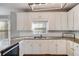 Well-lit kitchen showcasing granite counters, white cabinets, and a stainless steel sink under a window at 243 Yorkshire Ln, Villa Rica, GA 30180