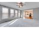 Spacious, carpeted living room with ceiling fan, large windows and view to the kitchen at 243 Yorkshire Ln, Villa Rica, GA 30180