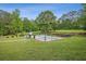 A large, covered in-ground pool is surrounded by lush greenery and decorative shrubs on a sunny day at 289 Barn Rd, Canton, GA 30115
