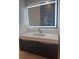 A modern bathroom vanity with a marble countertop, dark cabinets, and a large, illuminated mirror above at 2719 Winding Ne Ln, Brookhaven, GA 30319