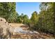 Spacious backyard featuring tiered landscaping, gravel pathways, and mature trees for ultimate privacy at 8380 Sentinae Chase Dr, Roswell, GA 30076