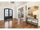Open foyer features wood floors, white columns, a large black front door, and an elegant entry table at 8380 Sentinae Chase Dr, Roswell, GA 30076