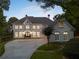 Charming exterior view showcasing arched windows, a circular driveway, and lush landscaping at 8380 Sentinae Chase Dr, Roswell, GA 30076
