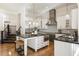 Open concept kitchen features a central island with seating, stainless steel appliances, and custom white cabinetry at 8380 Sentinae Chase Dr, Roswell, GA 30076