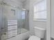 Clean, tiled bathroom featuring glass enclosed shower, tub, toilet, and window at 1250 Olympic Dr, Oxford, GA 30054