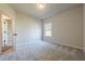 Neutral bedroom with wall to wall carpeting and window letting in natural light, a door open to the hallway at 30 Pinewood Dr, Covington, GA 30014