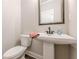 A powder room has a pedestal sink, framed mirror, white walls, and dark wood floors at 30 Pinewood Dr, Covington, GA 30014