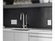 Modern kitchen sink with chrome faucet, white countertops, and black wood backsplash detail at 199 14Th St # 3003, Atlanta, GA 30309
