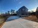 Two-story home with gray siding and a large driveway, nestled in a wooded area with blue skies at 1641 Fuma Leaf Way, Mcdonough, GA 30253