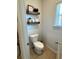 Small bathroom with a modern toilet, floating shelves with decorative items, and a window at 5257 Shorthorn Way, Powder Springs, GA 30127