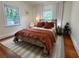 Bedroom with hardwood floors, two windows with curtains, and rust bedding at 91 Morris Brown Sw Dr, Atlanta, GA 30314