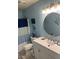 Bathroom with blue color scheme, round mirror, and white vanity and toilet at 2705 Greystone Pl, Austell, GA 30106