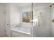 Modern bathroom featuring a tub and shower with glass screen, complemented by herringbone-patterned tiling and gold fixtures at 370 Charlyne Way, Dacula, GA 30019