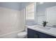 Stylish bathroom featuring a blue vanity, bathtub and shower combo, and a bright window at 2612 Grove Park Ln, Conyers, GA 30094