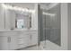 Modern bathroom with a double vanity, large mirror, and glass-enclosed shower with tile surround at 822 Urban Grange Way, Suwanee, GA 30024