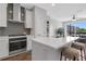 Modern kitchen with stainless steel appliances, gray backsplash, and a breakfast bar with stools at 822 Urban Grange Way, Suwanee, GA 30024