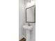 Clean powder room with a pedestal sink, framed mirror, and modern lighting fixtures at 822 Urban Grange Way, Suwanee, GA 30024