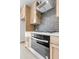 Modern kitchen with gray subway tile backsplash, stainless steel oven, and light wood cabinets at 913 Echo Park Dr, Suwanee, GA 30024