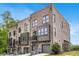Modern townhome exterior with brick facade, balconies, and attached garages against a blue sky backdrop at 923 Echo Park Dr, Suwanee, GA 30024