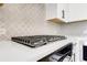 Close up of a kitchen backsplash, gas cooktop, and white countertop at 923 Echo Park Dr, Suwanee, GA 30024