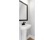 Stylish powder room featuring a pedestal sink with a black framed mirror at 923 Echo Park Dr, Suwanee, GA 30024