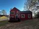 Red two-story home with a backyard deck, a partially fenced yard, and mature trees at 7472 Wood Ct, Lithonia, GA 30058