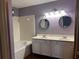 Bathroom featuring double sink vanity, granite countertop, tiled walls, and a tub, offering style and comfort at 7472 Wood Ct, Lithonia, GA 30058