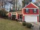 Charming red two-story home with black shutters, garage, and well-maintained landscaping at 7472 Wood Ct, Lithonia, GA 30058