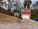 A red two-story home with a two-car garage, complemented by a cozy front yard at 7472 Wood Ct, Lithonia, GA 30058