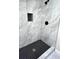 Walk-in shower with gray marble tile and black herringbone floor tile at 204 Apple Branch Dr, Woodstock, GA 30188