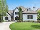 Charming two-story home with manicured lawn, arched windows, dark trim, and tasteful landscaping at 220 Windsor Gate Ne Cv, Atlanta, GA 30342