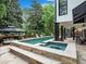 Backyard pool featuring an integrated spa and outdoor dining area with stone deck at 220 Windsor Gate Ne Cv, Atlanta, GA 30342